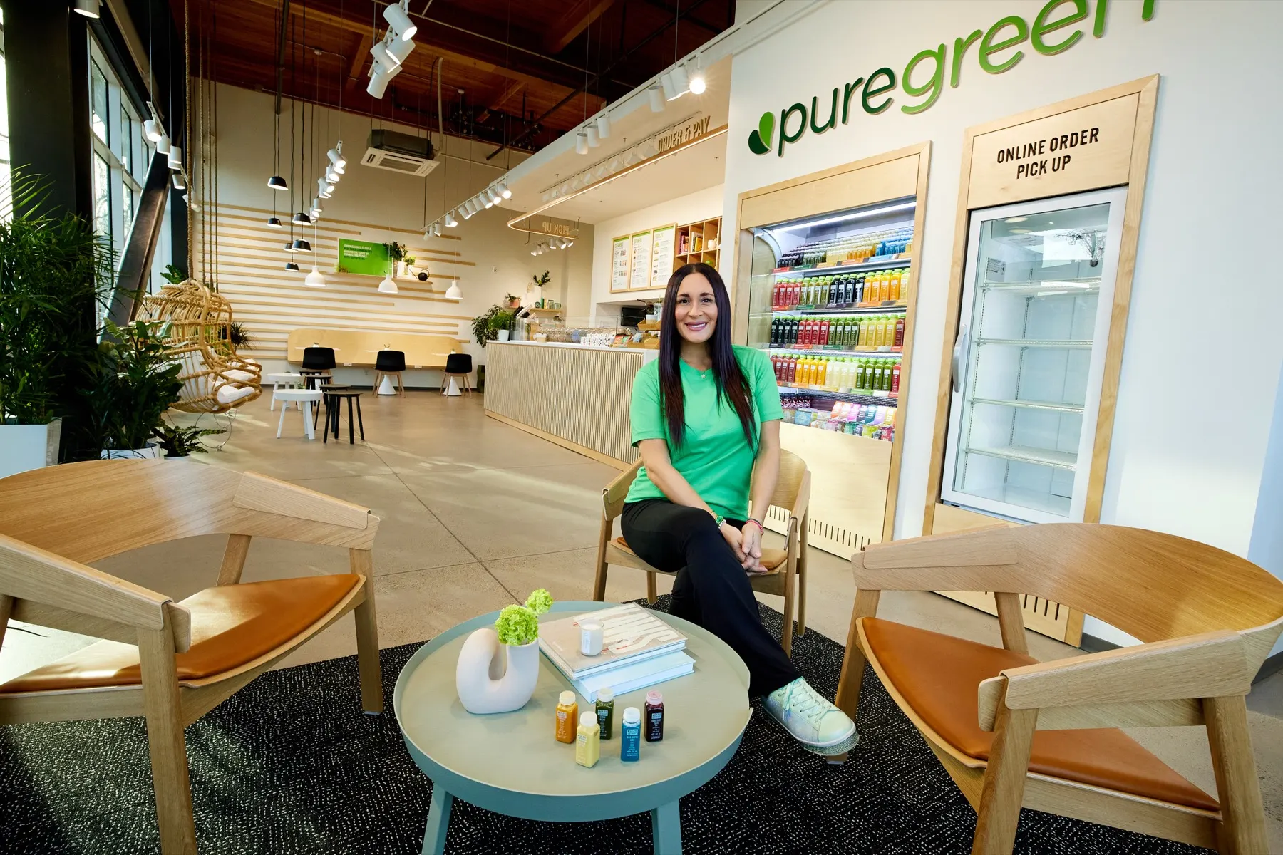 Inside a bright Pure Green store, a smiling team member sits in the lounge area